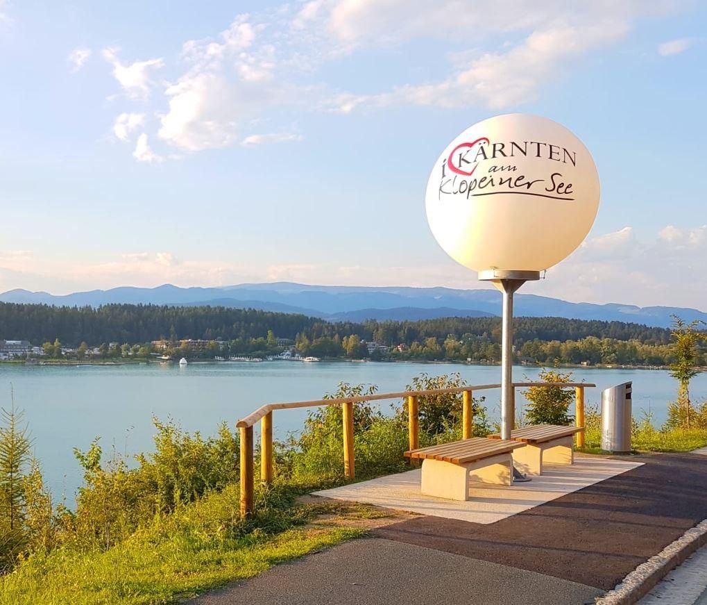 Aussichtspunkt über dem Klopeiner See mit Holzgeländer, Sitzbank und kugelförmiger Skulptur mit Kärnten-Schriftzug
